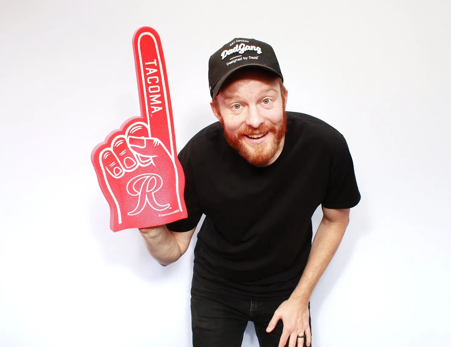 A TBD Photo Booths attendant grinning in the booth with a Tacoma Rainiers foam finger